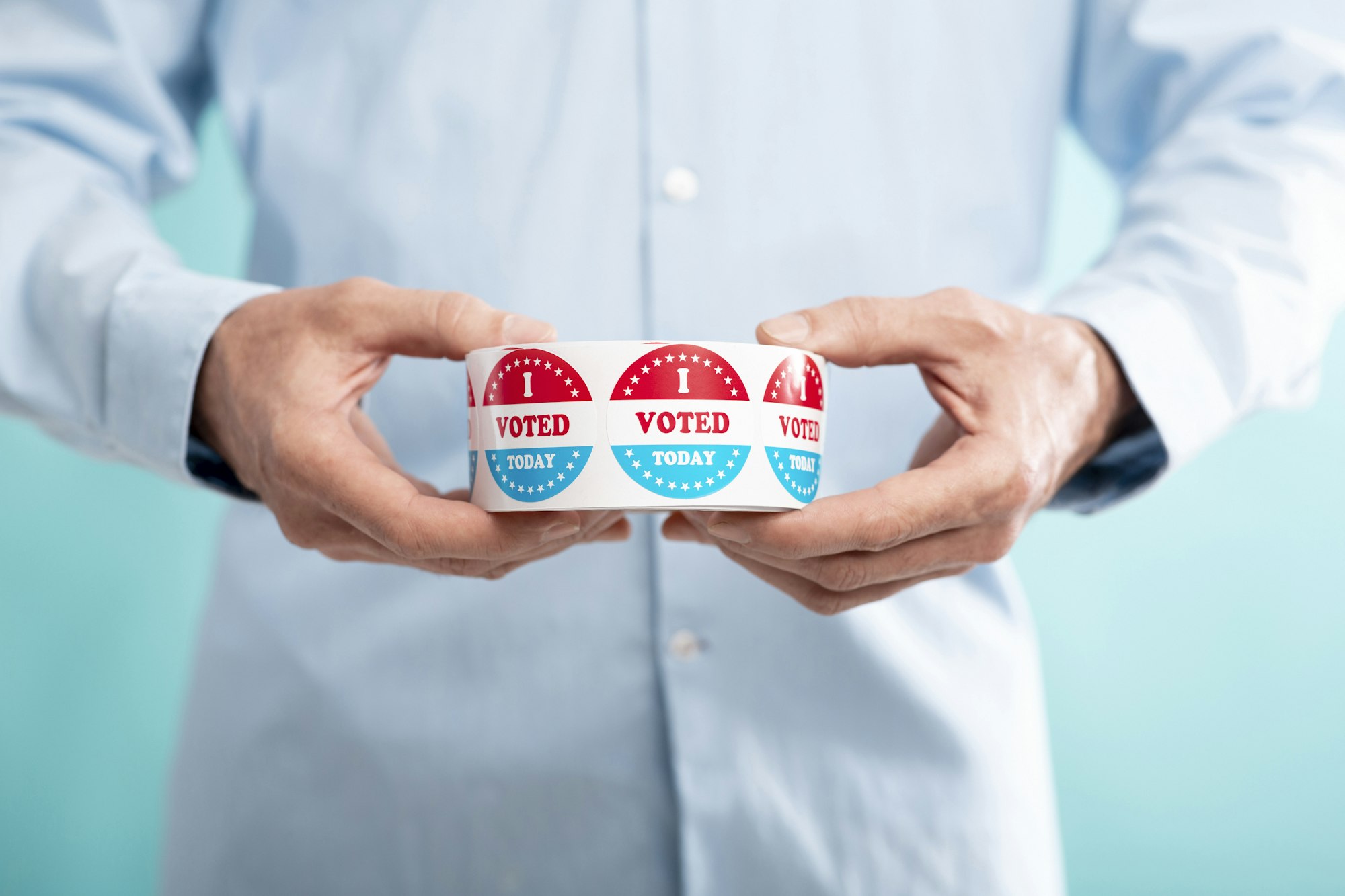 Unrecognizable man holding roll with stickers for voters